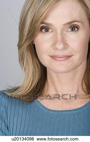 Stock Photo - Studio shot portrait of mature woman with hand on chin, close-up. Fotosearch