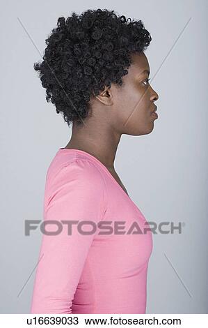 Stock Image - Studio shot portrait of mid adult woman, side view. Fotosearch