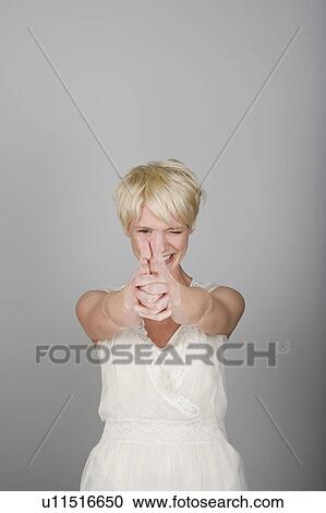 Stock Image - Studio shot portrait of mid adult woman aiming in viewer's side, waist up. Fotosearch