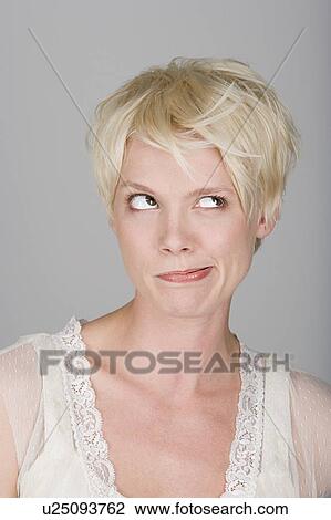 Stock Image - Studio shot portrait of mid adult woman blowing hair over face, close-up. Fotosearch