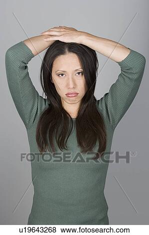 Stock Photo - Studio shot portrait of mid adult woman with arms raised, waist up. Fotosearch