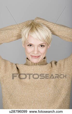 Stock Photo - Studio shot portrait of mid adult woman with hands behind head, head and shoulders. Fotosearch