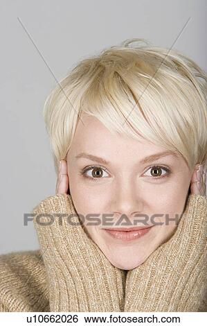 Stock Photograph - Studio shot portrait of mid adult woman with hand on chin, close-up. Fotosearch