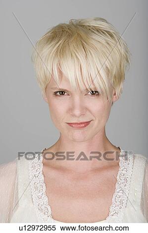 Stock Photography - Studio shot portrait of mid adult woman with tousled hair, close-up. Fotosearch