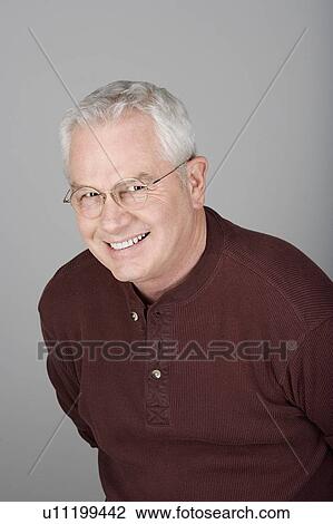 Stock Image - Studio shot portrait of smiling senior man, head and shoulders. Fotosearch