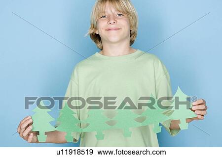 Stock Photo - Studio shot portrait of teenage boy holding paper chain, waist up. Fotosearch
