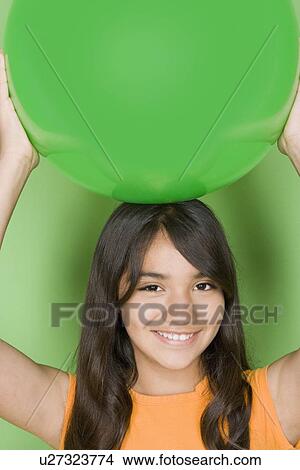 Studio shot portrait of teenage girl holding ball on her head, head and shoulders View Large Photo Image Picture - Studio shot portrait of teenage girl holding ball on her head, head and shoulders. Fotosearch