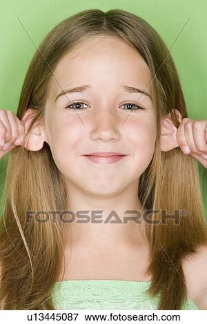 Stock Photo - Studio shot portrait of teenage girl pulling her ears, close-up. Fotosearch
