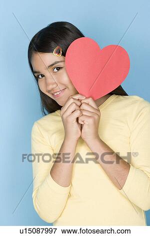 Stock Photo - Studio shot portrait of teenage girl holding hart, waist up. Fotosearch