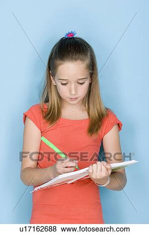 Stock Photo - Studio shot portrait of teenage girl writing in notebook, waist up. Fotosearch