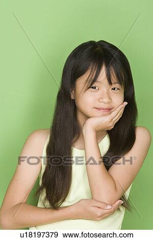 Stock Photo - Studio shot portrait of teenage girl with hand on chin, waist up. Fotosearch