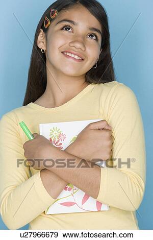 Studio shot portrait of teenage girl holding notebook, waist up View Large Photo Image Stock Photo - Studio shot portrait of teenage girl holding notebook, waist up. Fotosearch
