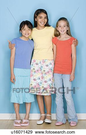 Stock Photo - Studio shot portrait of three teenage girls, full length. Fotosearch