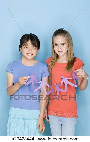 Studio shot portrait of two teenage girls holding paper chain, three quarter length View Large Photo Image Picture - Studio shot portrait of two teenage girls holding paper chain, three quarter length. Fotosearch