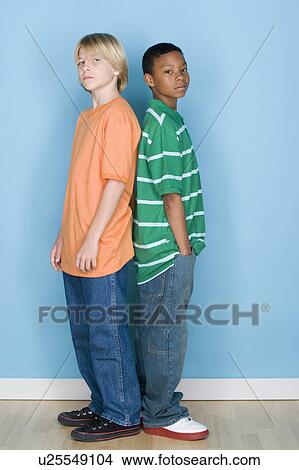 Picture - Studio shot portrait of two teenagers standing back to back, full length. Fotosearch
