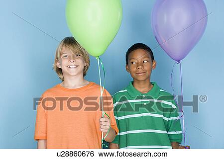 Stock Photograph - Studio shot portrait of two teenagers with balloons, head and shoulders. Fotosearch