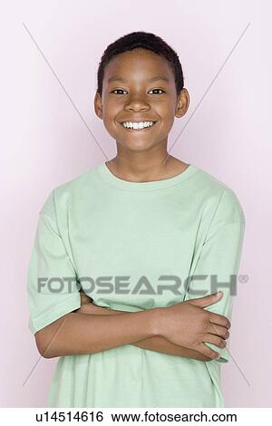 Stock Photograph - Studio shot portrait of young man with crossed arms, waist up. Fotosearch