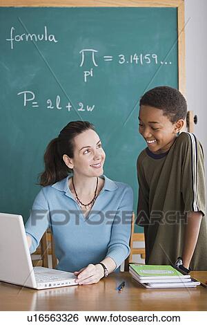 Stock Photograph - Teacher with schoolboy in classroom. Fotosearch