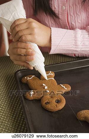 Stock Photo - Teenage girl (16-17) decorating gingerbread with icing. Fotosearch