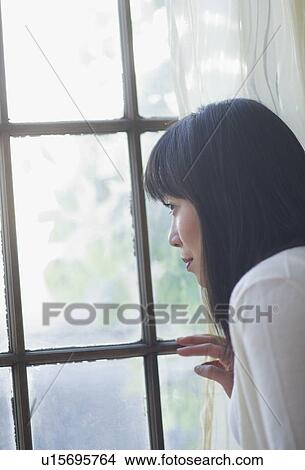 Picture - Thoughtful woman looking through window. Fotosearch