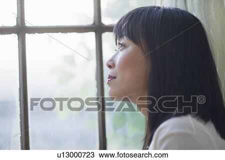 Stock Image - Thoughtful woman looking through window. Fotosearch