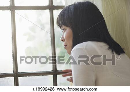 Thoughtful woman looking through window View Large Photo Image Stock Photograph - Thoughtful woman looking through window. Fotosearch