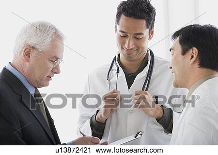 Three doctors discussing View Large Photo Image Stock Image - Three doctors discussing. Fotosearch