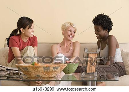 Three female friends sitting on sofa and talking View Large Photo Image Stock Photo - Three female friends sitting on sofa and talking. Fotosearch