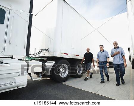 Three men walking between trucks View Large Photo Image Picture - Three men walking between trucks. Fotosearch