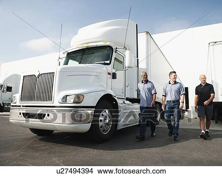Picture - Three men walking between trucks. Fotosearch
