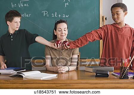 Two boys holding apples in front of teacher View Large Photo Image Stock Image - Two boys holding apples in front of teacher. Fotosearch