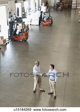 Two businessmen shaking hands in warehouse View Large Photo Image Stock Photo - Two businessmen shaking hands in warehouse. Fotosearch