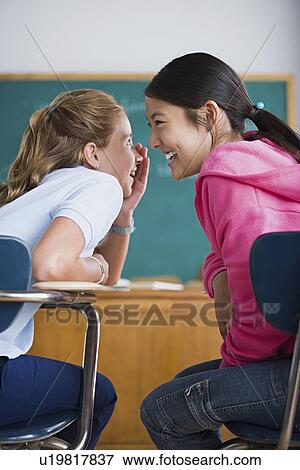 Two girls gossiping in classroom View Large Photo Image Stock Photo - Two girls gossiping in classroom. Fotosearch