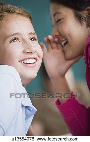 Two girls gossiping View Large Photo Image Stock Photo - Two girls gossiping. Fotosearch