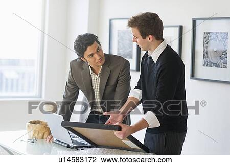 Stock Image - Two men working in art gallery. Fotosearch