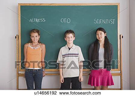 Two schoolgirls and schoolboy standing against blackboard with profession names written above View Large Photo Image Stock Image - Two schoolgirls and schoolboy standing against blackboard with profession names written above. Fotosearch