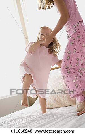 Stock Photo - Two sisters dancing on bed. Fotosearch