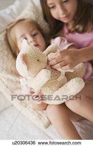 Two sisters playing with teddy bear View Large Photo Image Stock Photograph - Two sisters playing with teddy bear. Fotosearch