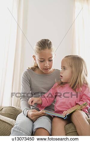 Stock Image - Two sisters reading book. Fotosearch