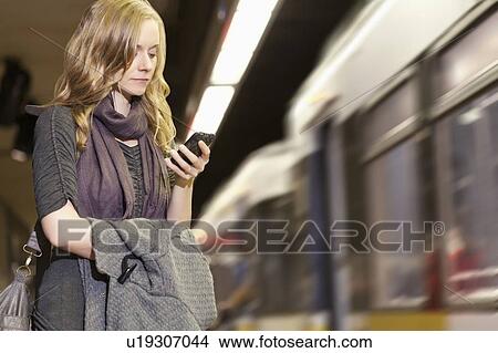 Picture - USA, California, Los Angeles, Woman sending text messages on subway station. Fotosearch