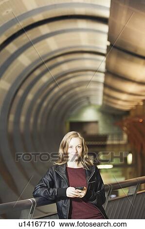 Stock Image - USA, California, Los Angeles, Woman sending text messages on subway station. Fotosearch