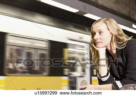 Stock Photo - USA, California, Los Angeles, Woman sitting on subway station. Fotosearch