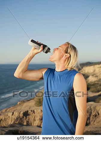 Picture - USA, California, San Diego, Male jogger drinking water from bottle. Fotosearch