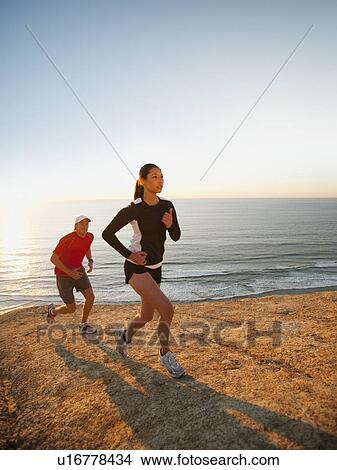 Picture - USA, California, San Diego, Man and woman jogging along sea coast. Fotosearch