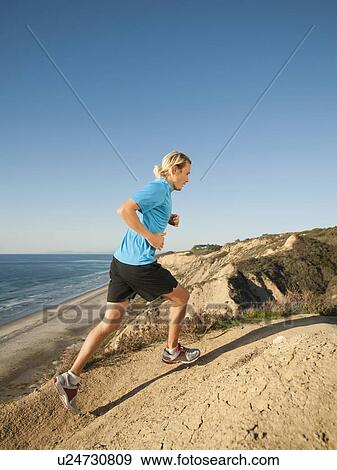 Stock Photo - USA, California, San Diego, Man jogging along sea coast. Fotosearch