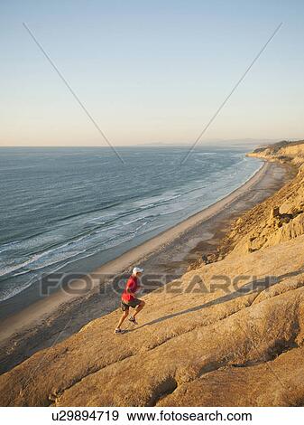 Stock Photo - USA, California, San Diego, Man jogging along sea coast. Fotosearch