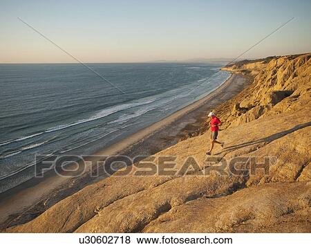 Stock Photo - USA, California, San Diego, Man jogging along sea coast. Fotosearch