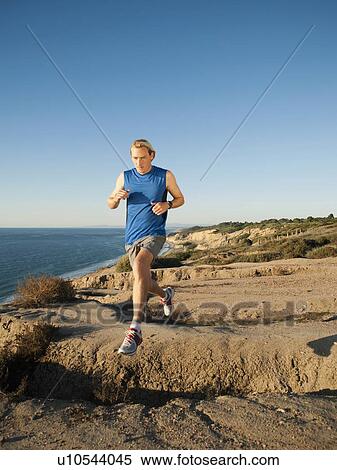 Stock Photography - USA, California, San Diego, Man jogging along sea coast. Fotosearch