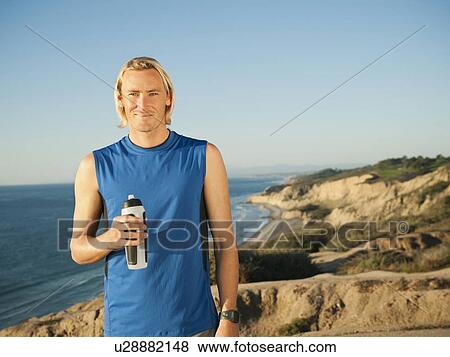 USA, California, San Diego, Portrait of male jogger holding water bottle View Large Photo Image Stock Photo - USA, California, San Diego, Portrait of male jogger holding water bottle. Fotosearch