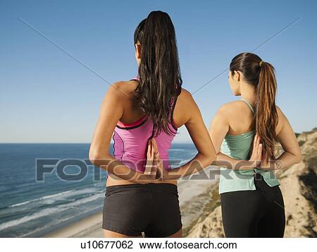 Stock Image - USA, California, San Diego, Two women practicing yoga on beach. Fotosearch
